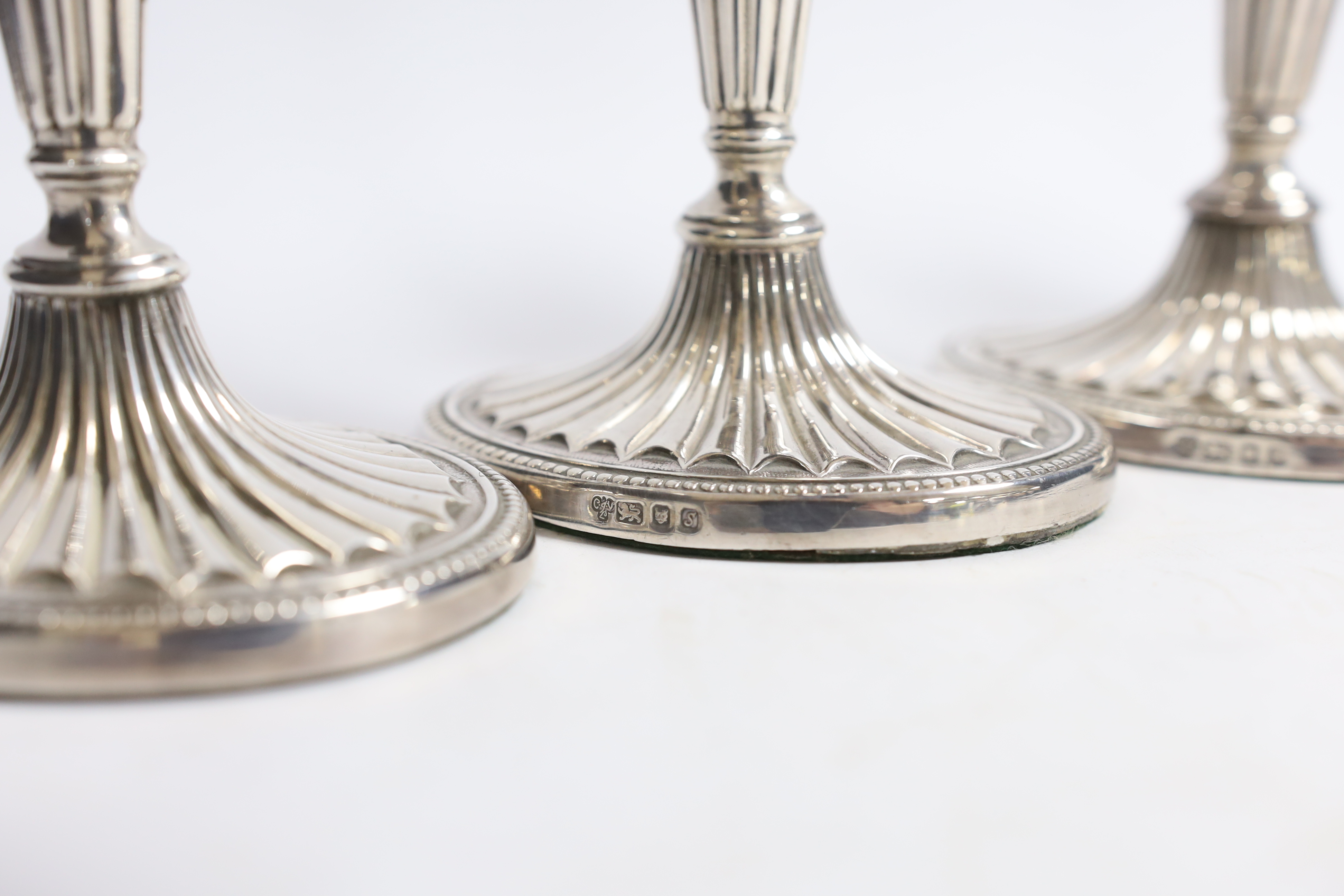 A set of four Elizabeth II silver candlesticks, with fluted stems and bases, C.J. Vander Ltd, London, 1973, 17.2cm, weighted.